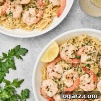 Shrimp scampi with orzo pasta served in white bowls, garnished with parsley and lemon wedges.