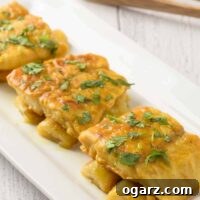 An oblong serving plate with three pieces of pan-fried fish fillets served over bananas sautéed in a light curry sauce.