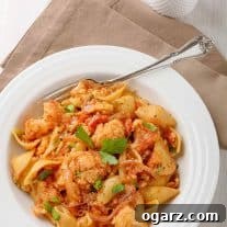 Rustic Sicilian Cauliflower Pasta 4 A delightful bowl of Sicilian pasta with cauliflower, featuring shell pasta combined with tender steamed cauliflower, sweet raisins, crunchy pine nuts, savory diced tomatoes, and a subtle hint of anchovies, all harmoniously blended.