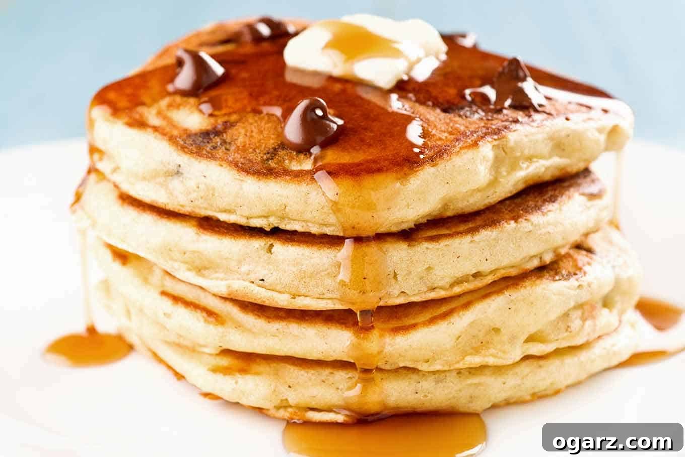 Decadent Chocolate Chip Pancakes with Crispy Candied Bacon 3 A stack of four chocolate chip and candied bacon pancakes topped with a few extra chocolate chips, a pat of butter, and a drizzle of maple syrup.