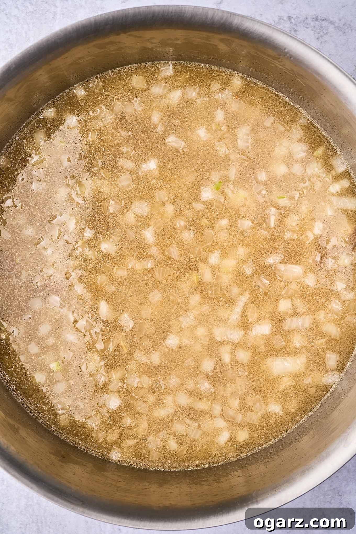 Smoky Bacon & Tomato Corn Chowder 5 A soup pot showcasing potatoes simmering in a rich chicken broth, infused with the savory flavors of sautéed onion and garlic, forming the hearty base of the corn chowder.