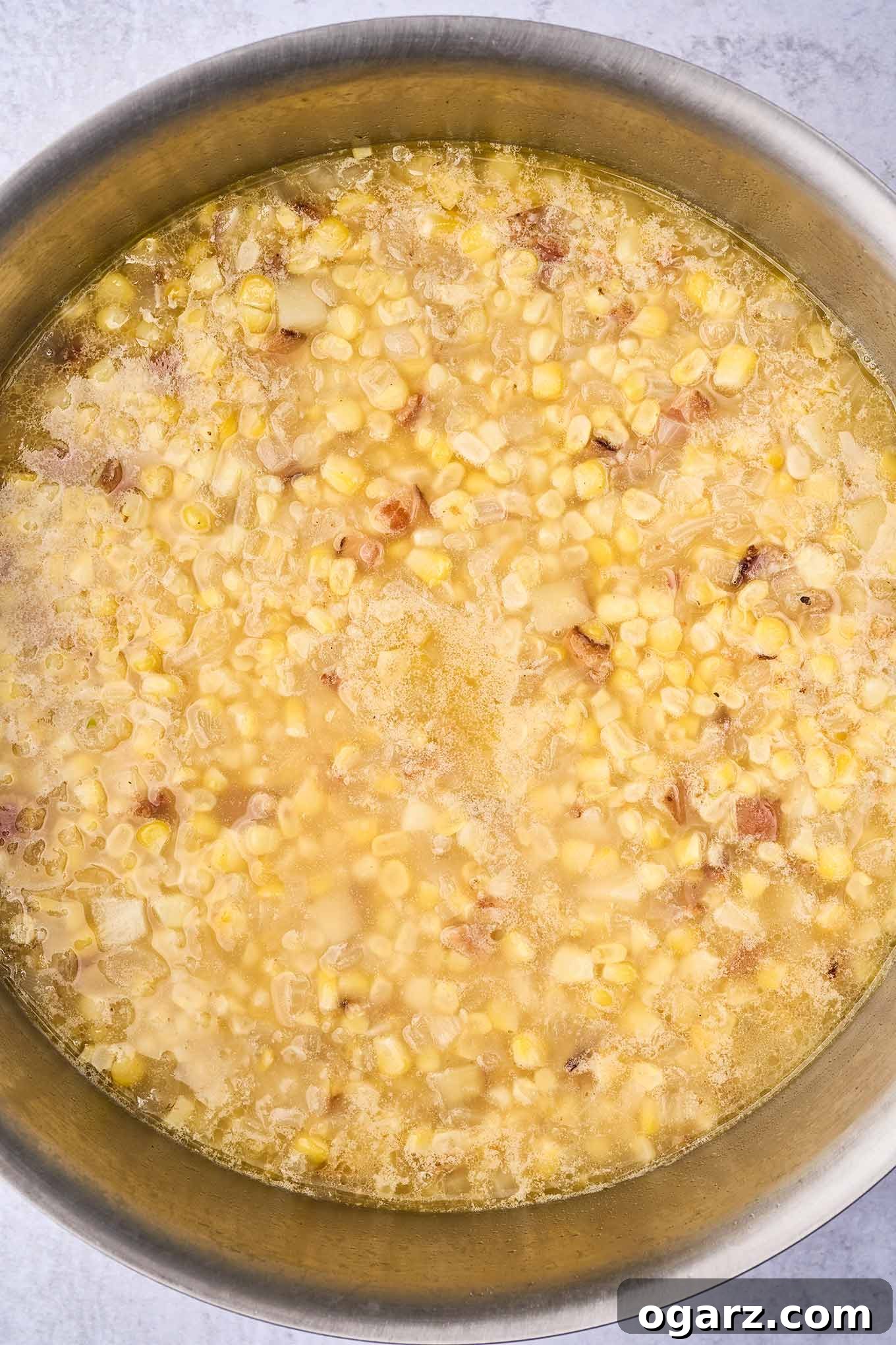 Smoky Bacon & Tomato Corn Chowder 6 A large soup pot containing chicken broth, tender potato chunks, and fresh corn kernels, ready for the next step of pureeing some of the mixture to create a creamy texture while preserving other solids.