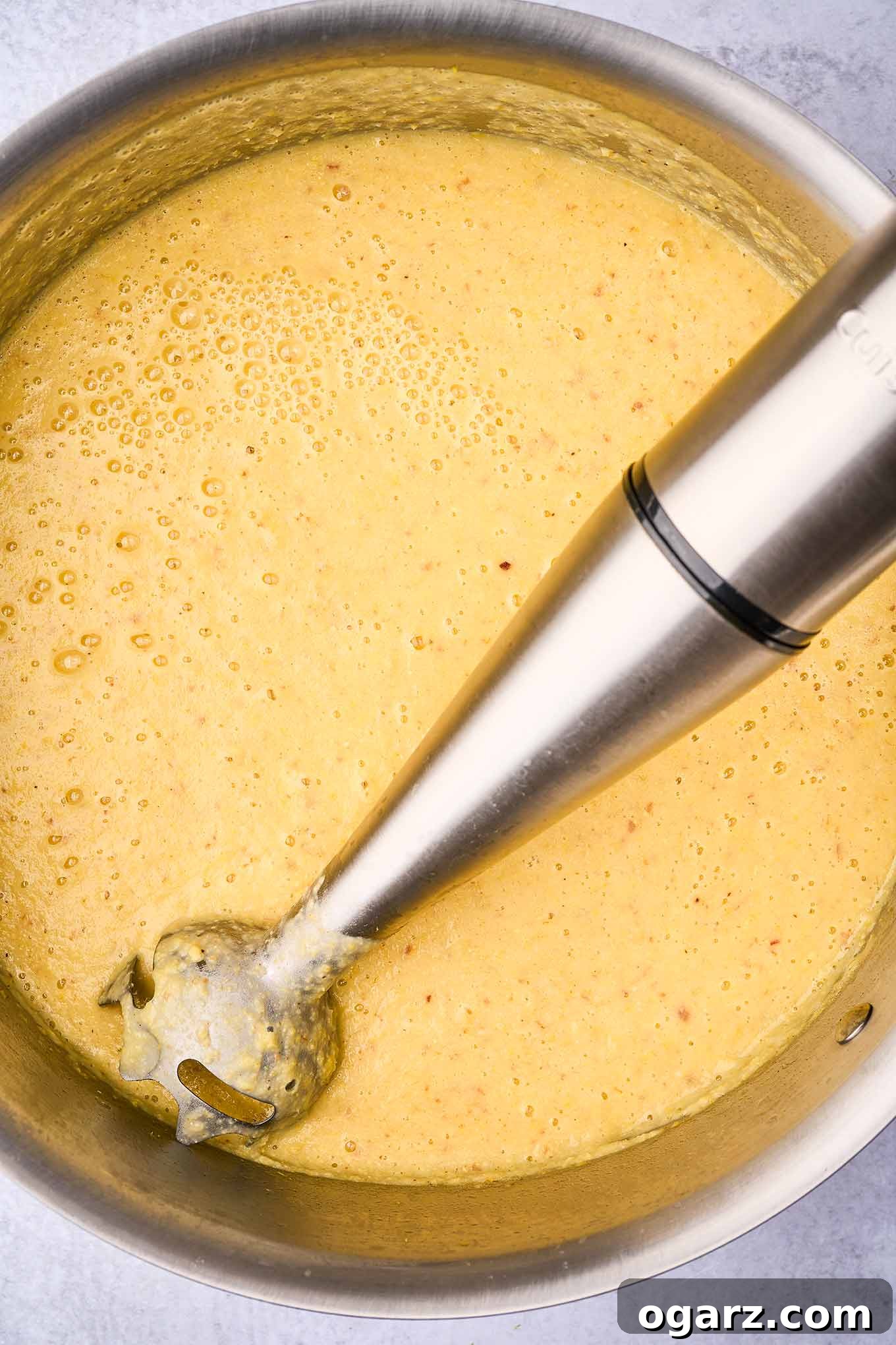 Smoky Bacon & Tomato Corn Chowder 7 An immersion blender actively puréeing creamy corn chowder within a large soup pot, creating a smooth and luscious texture for the soup base.