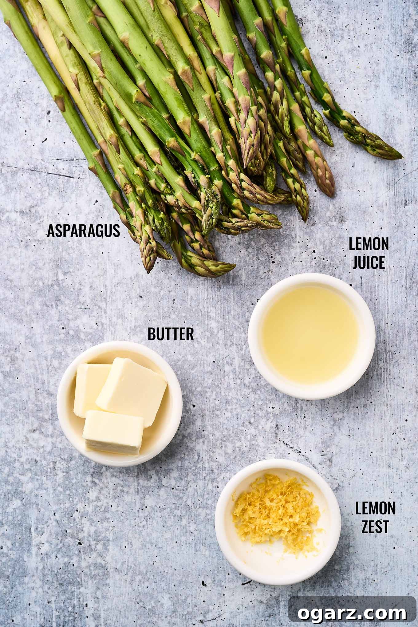 Zesty Roasted Asparagus 3 A labeled, overhead view of the ingredients needed for making lemon roasted asparagus; fresh asparagus spears, buttter, lemon juice and zest.