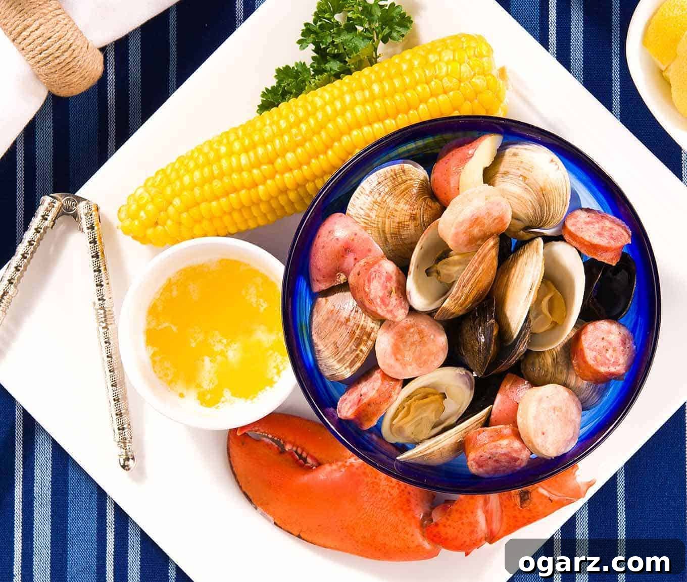 Home Clambake Delight 3 A beautifully arranged plate featuring a vibrant lobster claw, a golden ear of corn, a small bowl of rich melted butter, a sturdy nutcracker, and a delectable medley of steamed clams, mussels, smoked sausage, and red potatoes, showcasing a classic clambake serving.
