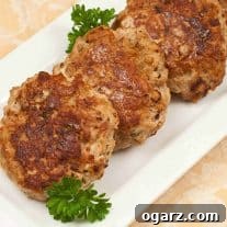 Golden-brown turkey meatloaf patties arranged on a white rectangular platter, garnished with fresh parsley.