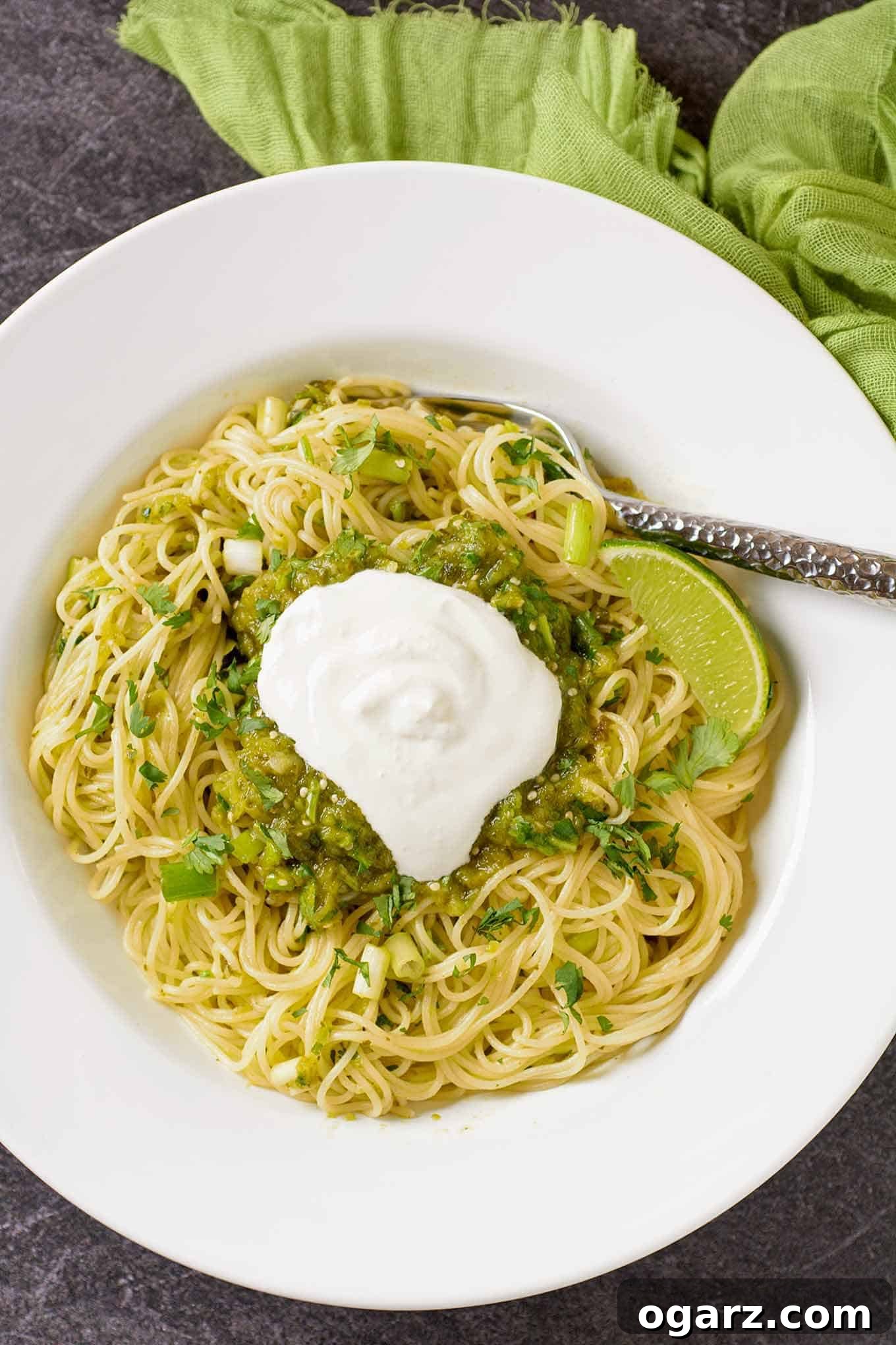 Thin spaghetti tossed with a vibrant salsa verde made with roasted tomatillos, poblano peppers, fresh lime, scallions, and cilantro, garnished with a dollop of sour cream and a fresh lime wedge.