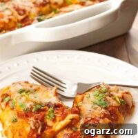 A plate of enchiladas filled with moist, tender chicken, melted cheese and cilantro and baked in a zesty homemade enchilada sauce, the casserole in the background.
