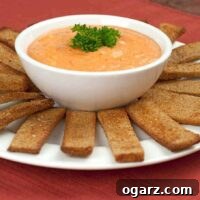 Close-up of a bowl of Roasted Red Pepper Dip, garnished and ready to serve.