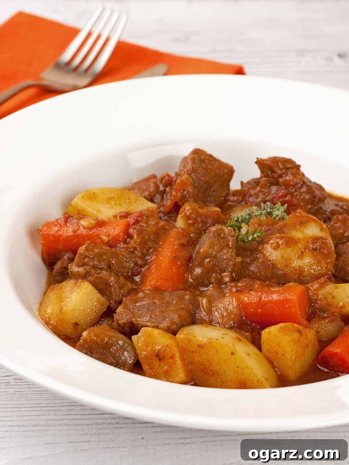 Succulent Pressure Cooker Beef Stew 2 A steaming bowl of tender pressure cooker beef stew, featuring succulent chunks of beef, vibrant potatoes, carrots, and a rich, savory brown gravy, beautifully garnished with fresh thyme sprigs.