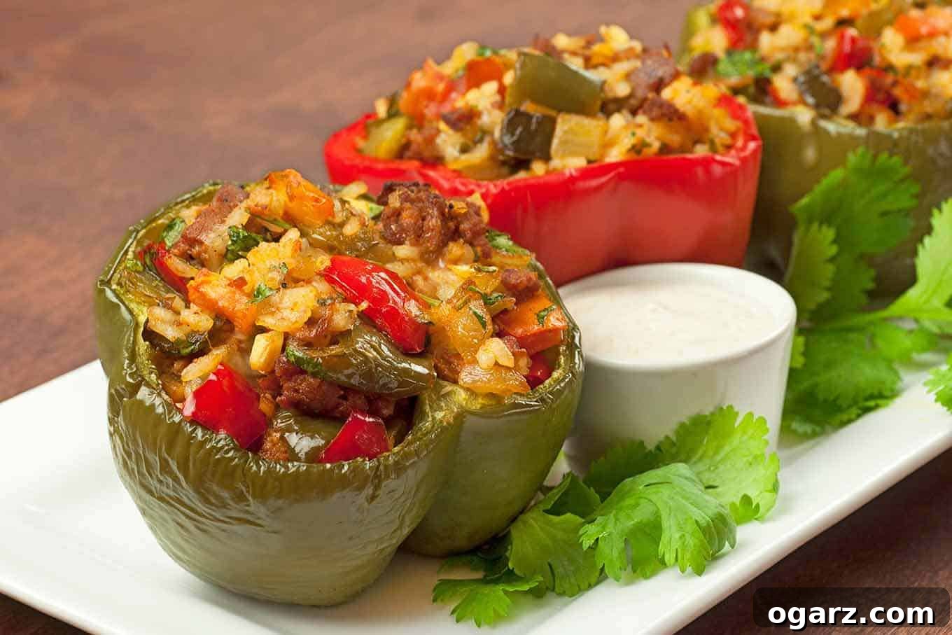 Fiery Chorizo Pepper Pockets 2 Colorful bell peppers stuffed with chopped peppers, chorizo, rice, and herbs, served on a white plate with a side of creamy dipping sauce and fresh cilantro garnish. This unique recipe incorporates part of the bell pepper into the savory filling for a lighter, more integrated flavor.