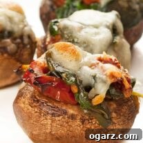Close-up photo of spinach stuffed mushrooms with melted cheese on top, served on a white plate.