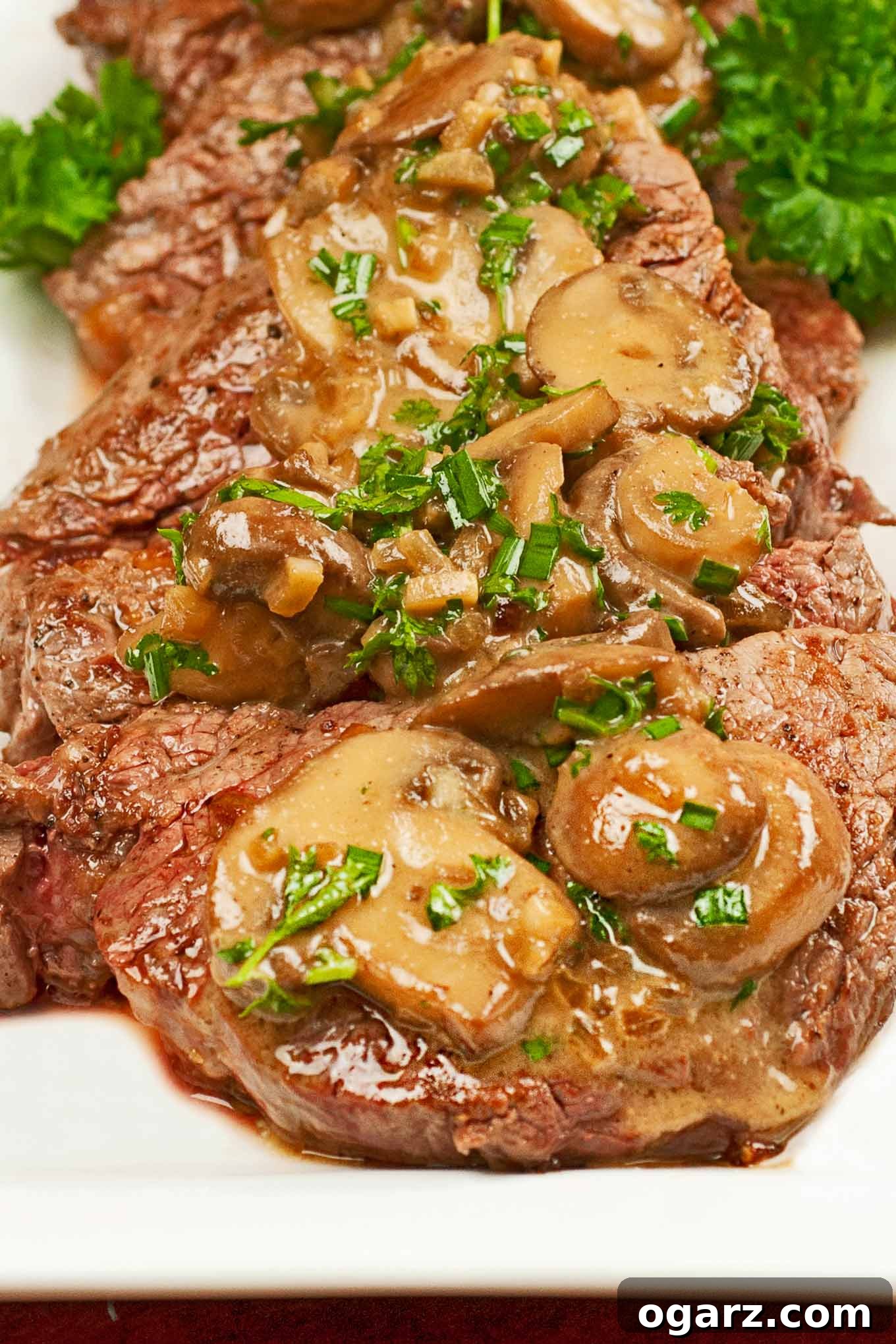 Classic Flambéed Steak Diane 2 A serving platter of medallions of beef tenderloin topped with sautéed mushrooms and a brandy cream sauce.
