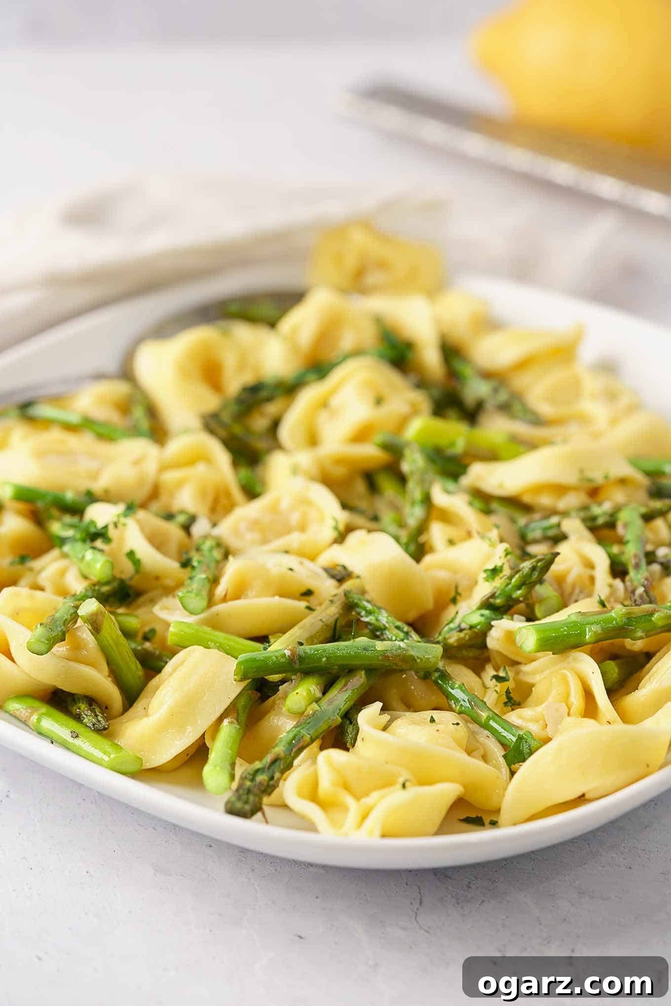 Tortellini with Asparagus and Lemon A serving plate filled with delicate cheese tortellini tossed with roasted asparagus, lemon zest, parsley, and a light cream sauce.