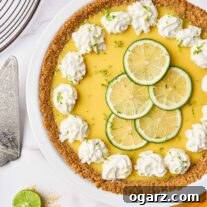 Sunshine State Key Lime Pie 7 Creamy Florida key lime pie filling in a white pie plate on a marble background, topped with thin lime slices, lime zest and dollops of whipped cream.