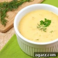 Close-up of a bowl of creamy Summer Squash Soup with Fresh Herbs, garnished with a swirl of sour cream and dill.