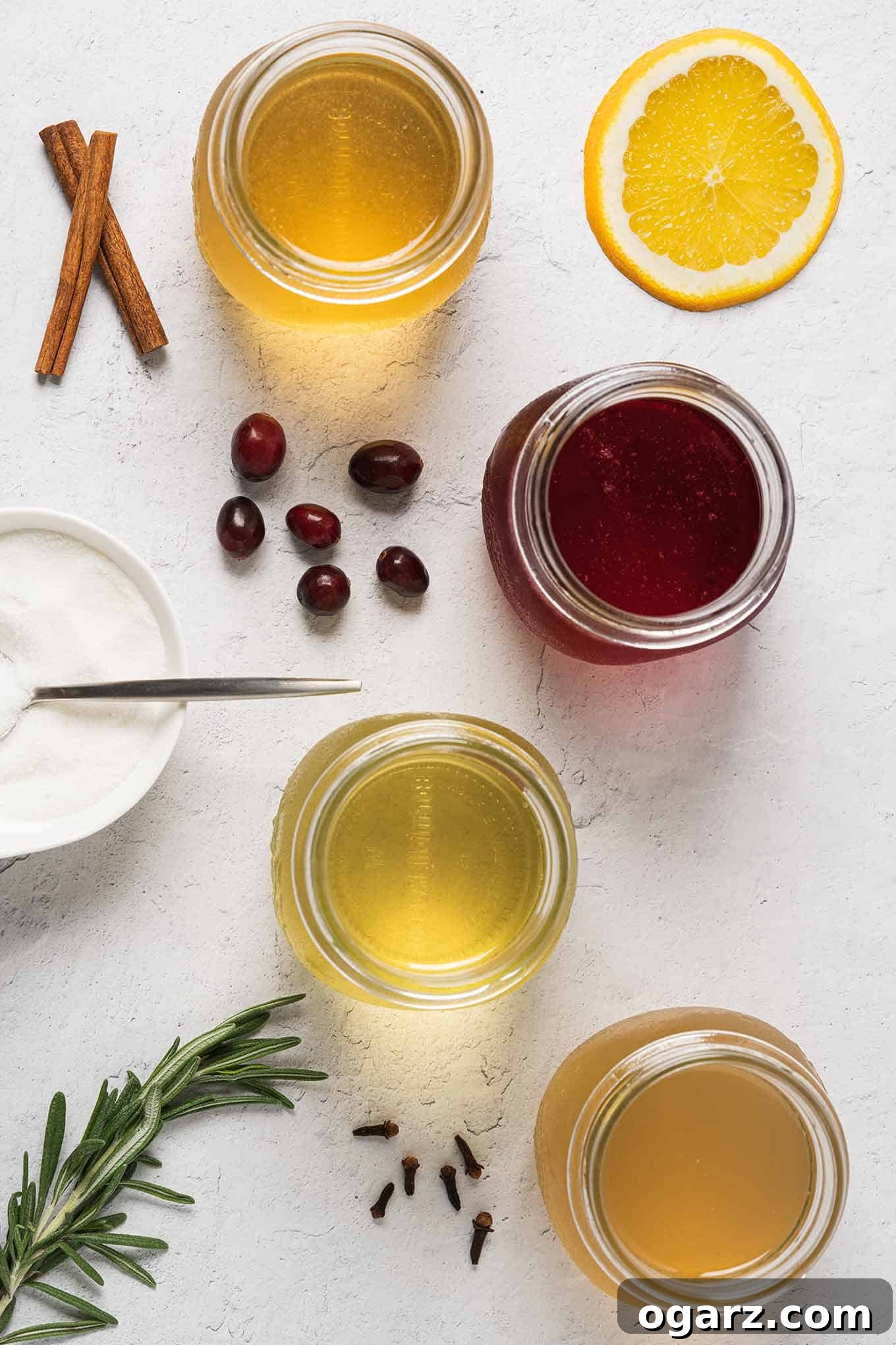 Yuletide Spiced Elixirs 4 An inviting overhead view showcasing four distinct Mason jars filled with homemade simple syrups: radiant orange, deep cranberry, verdant rosemary, and warm amber ginger. Fresh cranberries and other raw ingredients are elegantly scattered around them, highlighting the natural components of each syrup.