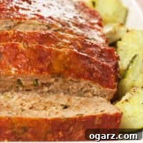 Tuscan Turkey Sausage Meatloaf 4 Sliced Italian turkey meatloaf on a serving platter surrounded by chunks of roasted zucchini.