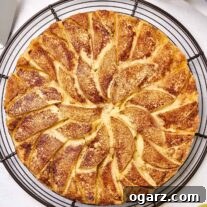 Freshly baked apple cake topped with sliced Golden Delicious apples and cinnamon sugar, cooling on a wire rack, waiting to be sliced.