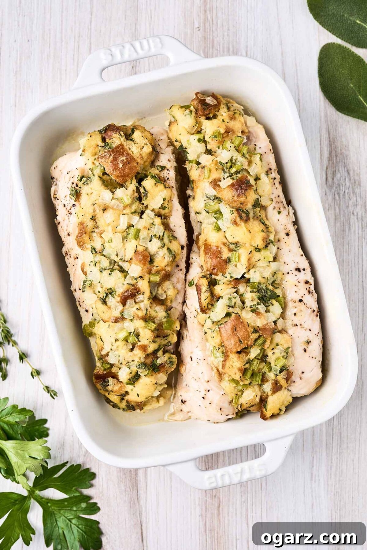 Succulent Baked Turkey Tenderloins with Savory Stuffing 10 Two stuffed turkey tenderloins in a white oblong baking dish surrounded by fresh parsley, sage and thyme.