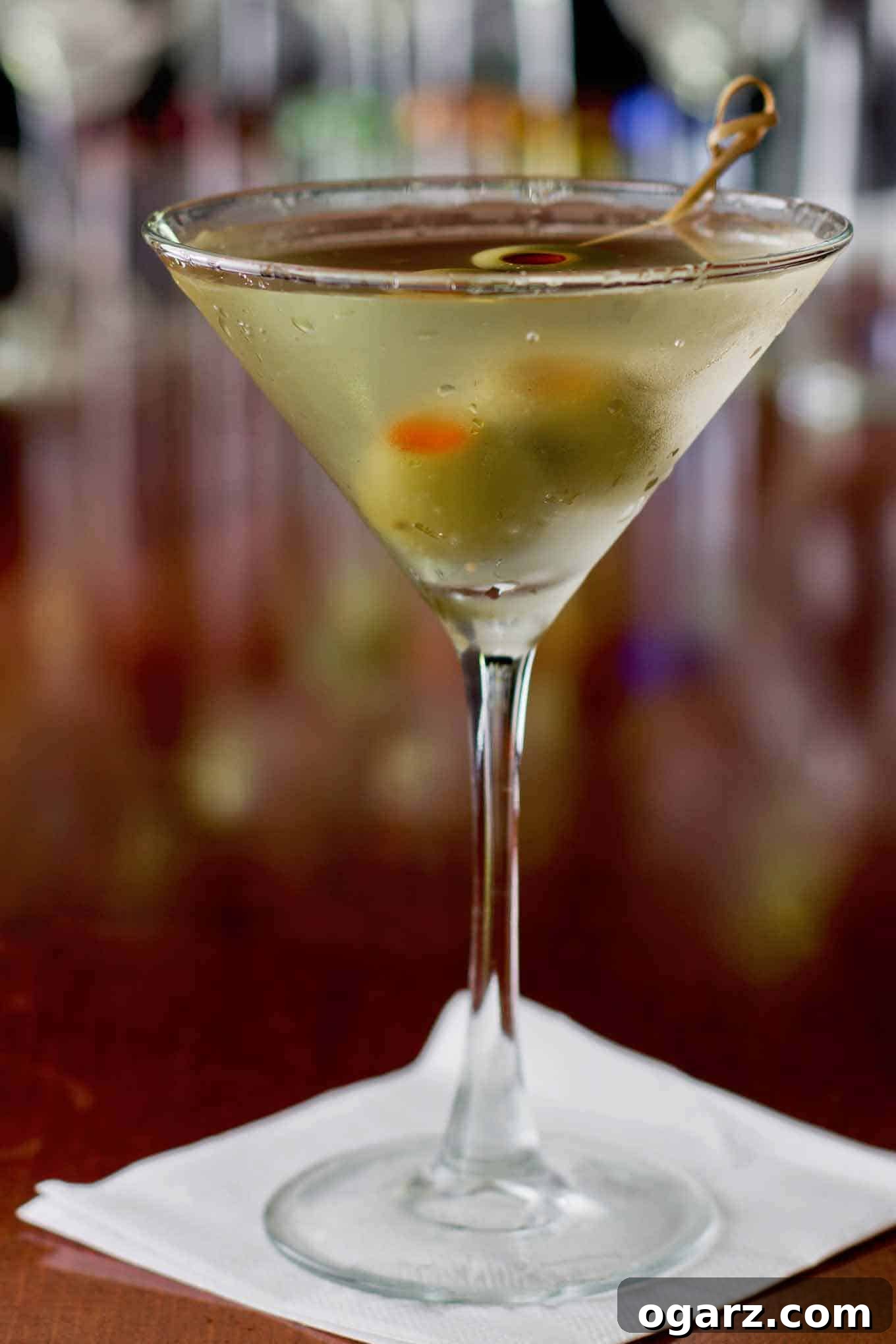 The Salty Secret 2 A dirty martini cocktail in a chilled glass with condensation on the outside and garnished with two olives.