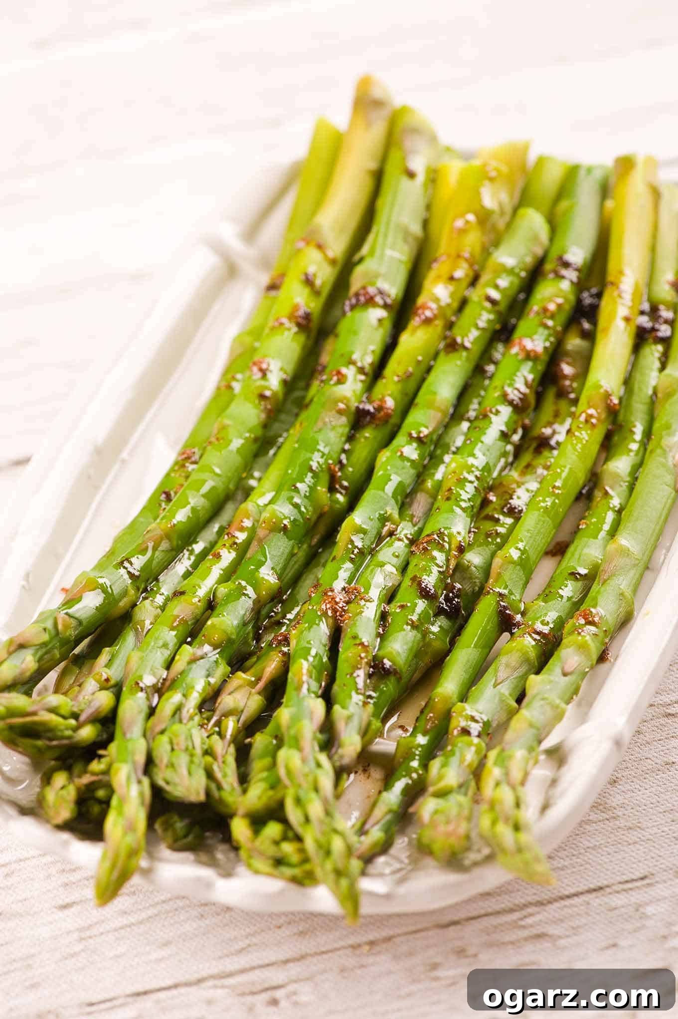 Nutty Brown Butter Asparagus 2 A platter of steamed asparagus drizzled with a combination of brown butter and balsamic vinegar, garnished with fresh black pepper.
