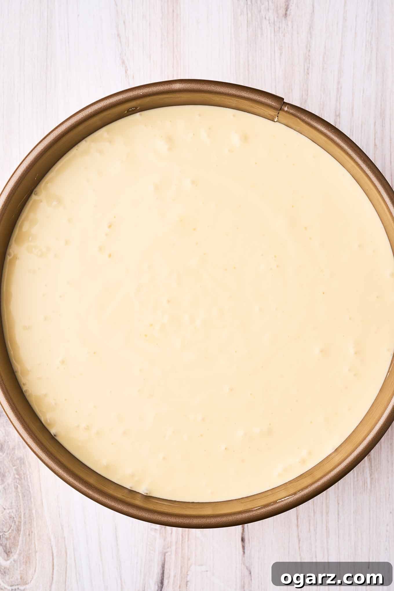 An overhead view of ricotta pie in a springform pan, ready for baking.