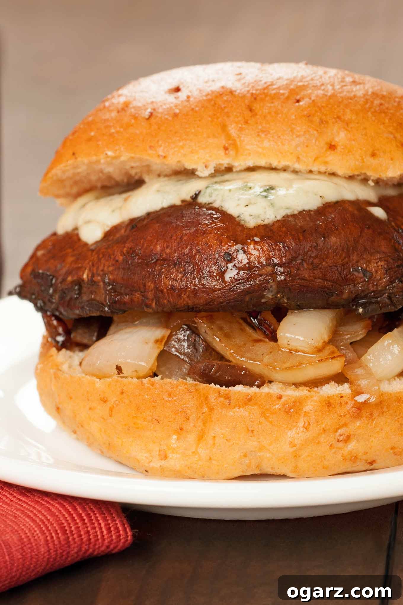 Sticky Balsamic Portobello Burgers 2 A close-up of a grilled portobello mushroom burger, richly glazed with balsamic, topped with sweet caramelized onions and a melted layer of tangy blue cheese. Served on a soft bun, this meatless marvel offers an irresistible alternative to traditional beef burgers.