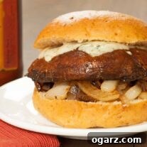 A side view of a balsamic glazed, grilled portobello mushroom on a soft hamburger bun with sautéed onions and creamy melted gorgonzola cheese.