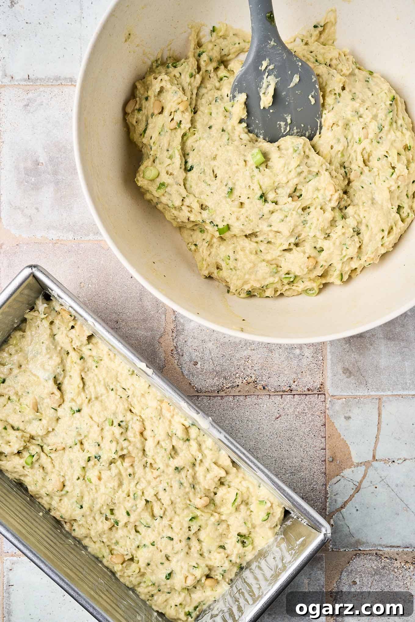 Herbed Zucchini Loaf 6 Pesto zucchini bread batter in a bowl with a spatula beside a loaf pan already filled and ready for baking.