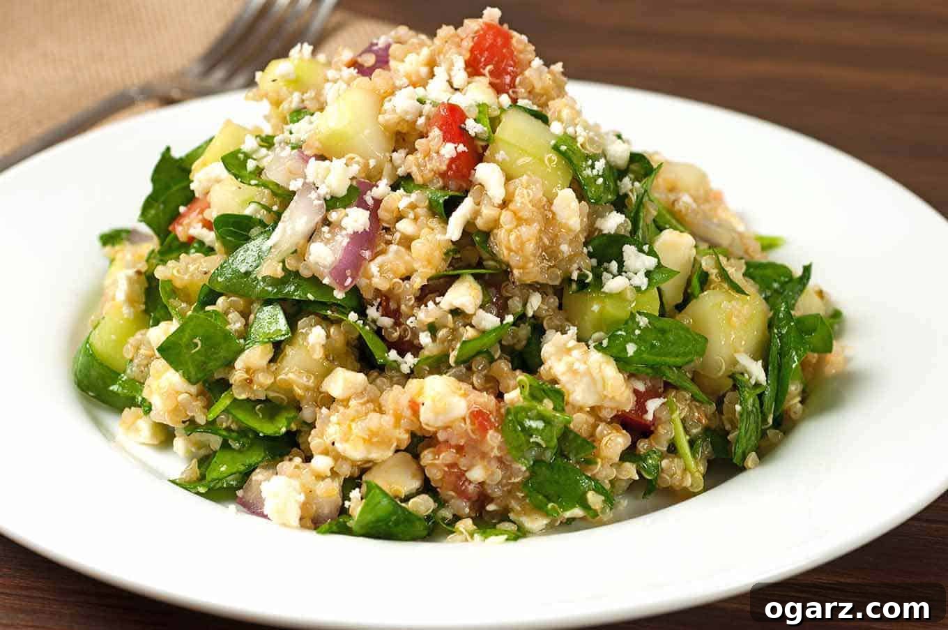 Close-up view of Greek spinach and quinoa salad, highlighting the texture of quinoa, crisp vegetables, and creamy feta.
