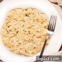 White bowl filled with creamy stovetop macaroni and cheese made with bowtie pasta, garnished with parsley, and served with a fork.