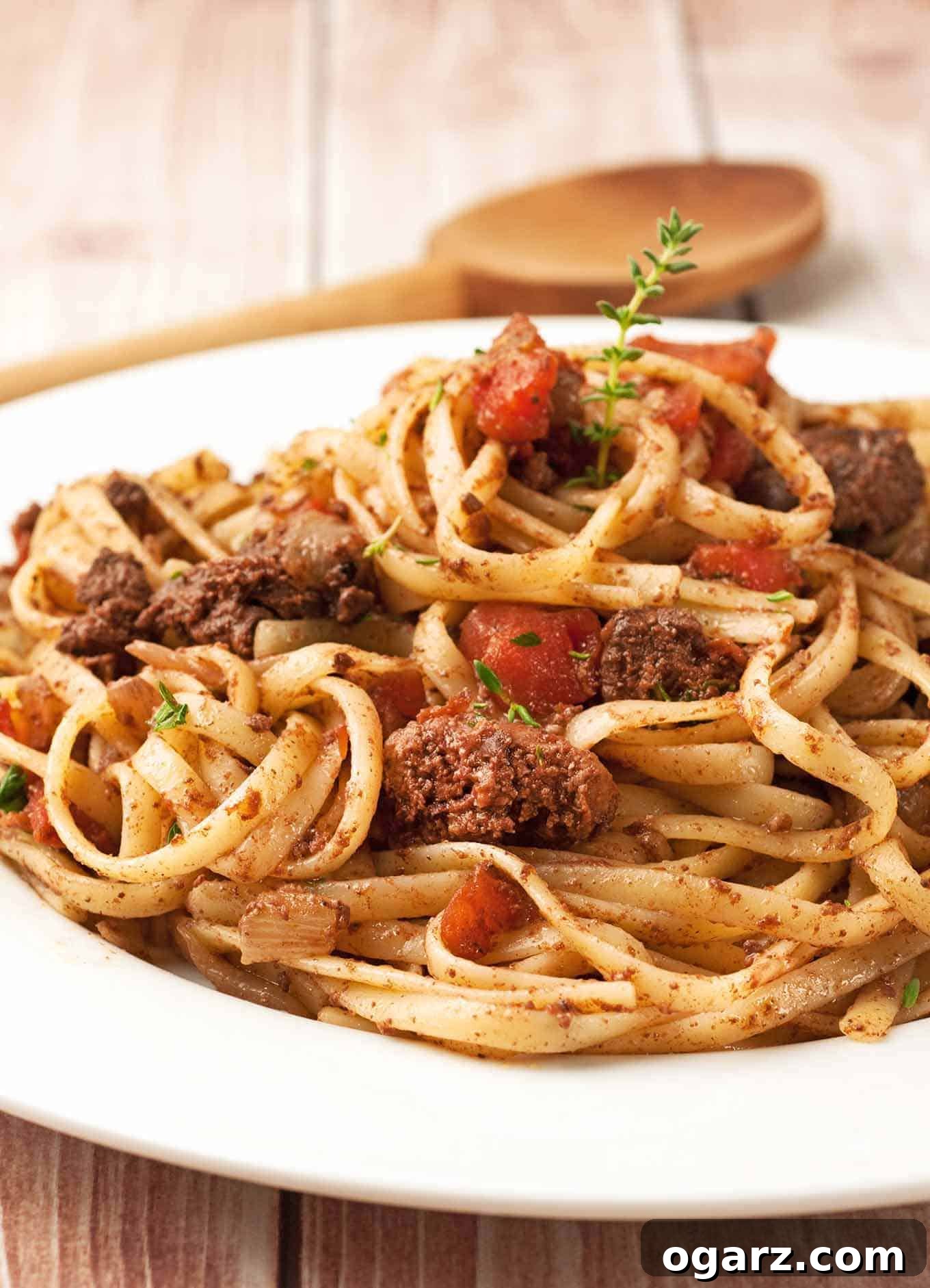 Braised Chicken Liver Ragu with Linguine 2 A plate of linguine topped with a rich chicken liver ragu, beautifully garnished with diced tomatoes and fresh thyme sprigs, showcasing the hearty and savory nature of the dish.