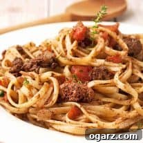 A plate of linguine topped with a rich chicken liver ragu, beautifully garnished with diced tomatoes and fresh thyme sprigs.