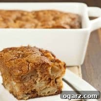 A single serving of spiced apple pudding cake on a plate with the whole cake in the background.
