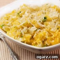 Spaghetti squash mixed with sautéed onion, garlic, and herbs, topped with grated cheese in a white bowl.