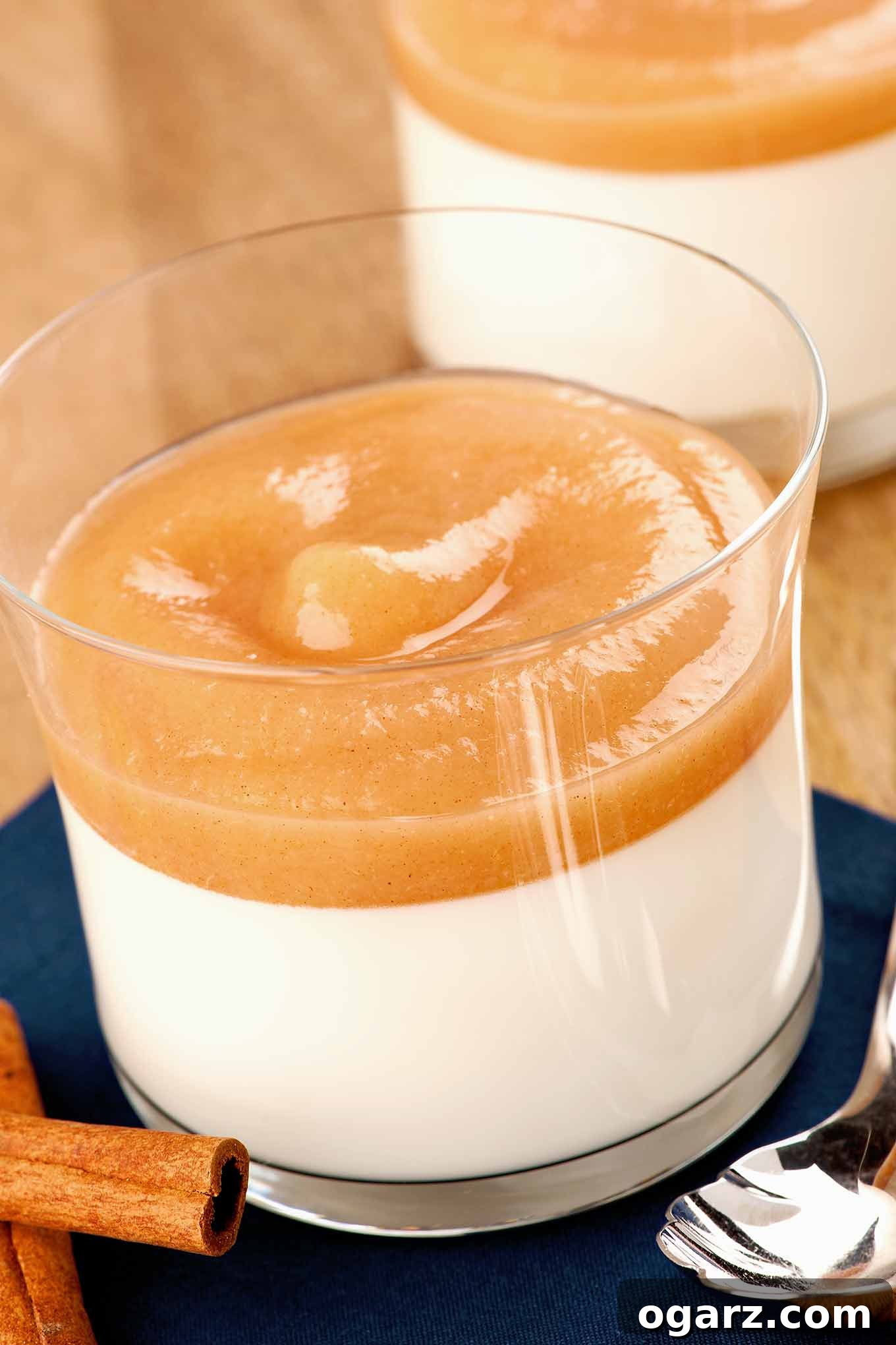 Aromatic Spiced Pear Panna Cotta 2 A single serving of elegant panna cotta topped with cinnamon-spiced pear puree in a clear glass, presented as a perfect fall dessert.