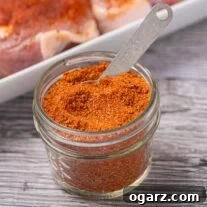 Homemade dry rub for pork chops in a glass jar with measuring spoon.