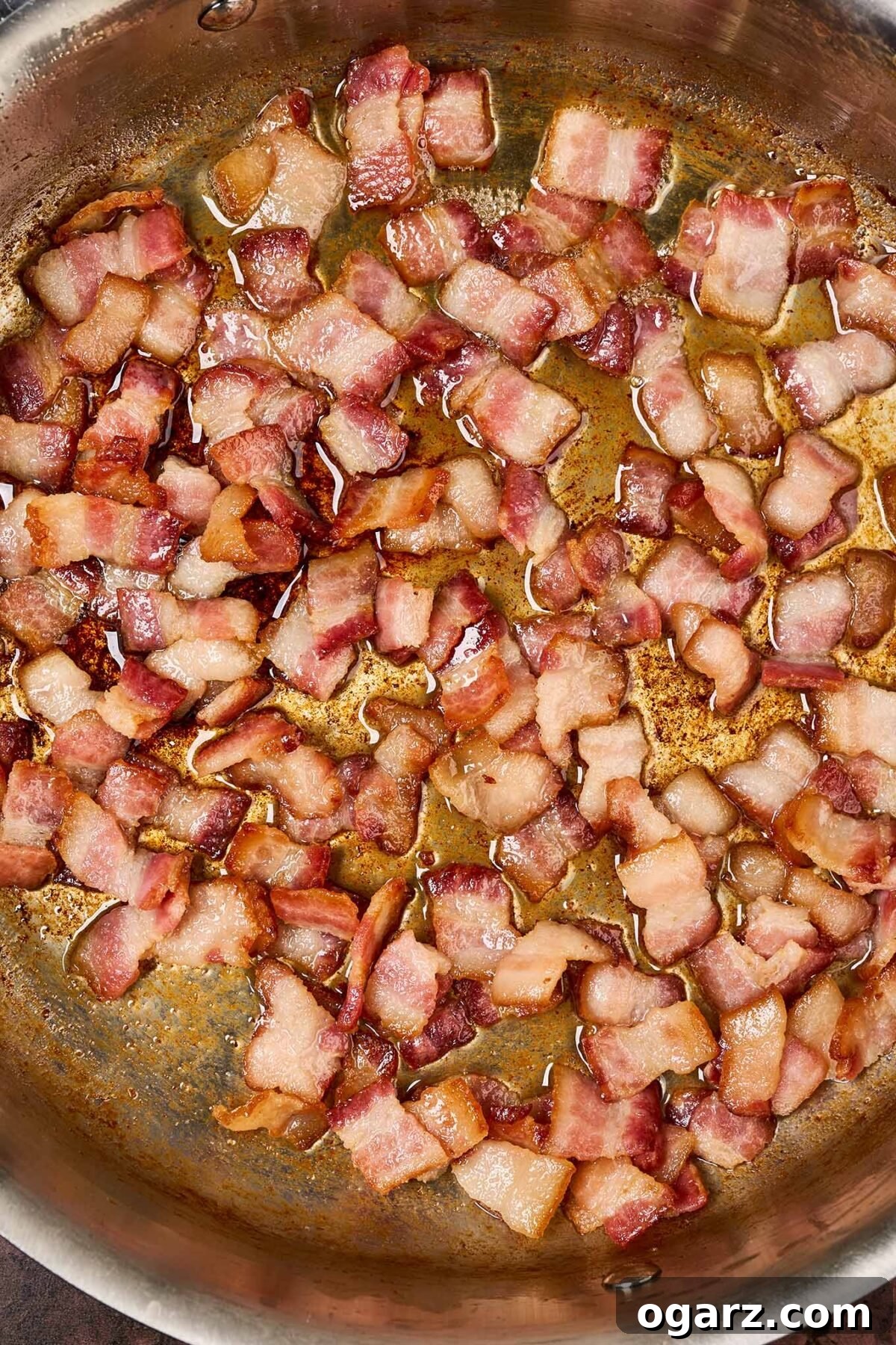 A frying pan filled with pieces of partially cooked, thick-cut bacon.
