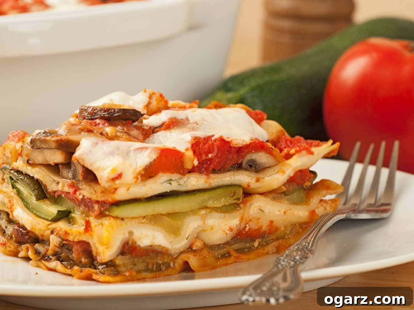 Garden Lasagna 3 A close-up view of a perfectly portioned slice of vegetable lasagna, showcasing distinct layers of golden-brown pasta, vibrant roasted vegetables (eggplant, zucchini, mushrooms), creamy ricotta, and melted mozzarella cheese, served on a clean white plate. The intricate structure and appetizing texture highlight the careful preparation of this healthy, vegetarian dish.