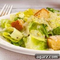 A serving of easy-to-make Caesar salad topped with garlic butter croutons and grated Parmesan cheese.