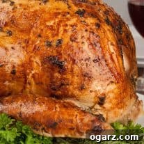 Golden Herb Turkey with a Mayonnaise Glaze 5 Mayonnaise and herb coated turkey with golden brown skin, ready for carving, on a platter garnished with fresh herbs, a glass of red wine in the background.