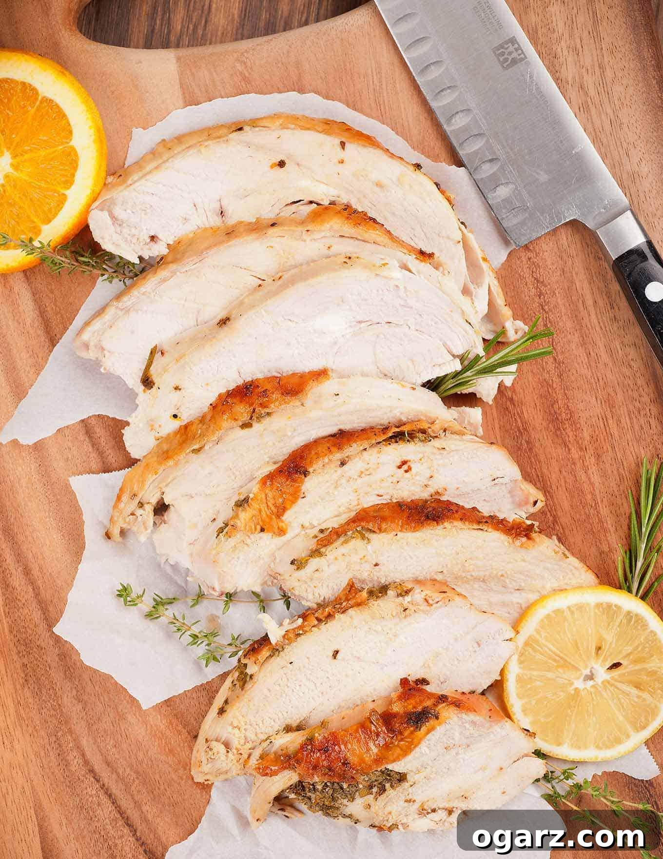 Zesty Herb Roasted Turkey Breast 3 Slices of perfectly roasted turkey breast on a cutting board, accompanied by a carving knife, fresh sprigs of herbs, and vibrant lemon and orange slices, highlighting the golden-brown skin.