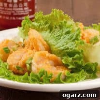 A close view of Bang Bang shrimp lettuce wraps on a white plate with a bottle of sriracha in the background.