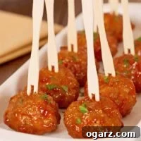 Whiskey glazed cocktail meatballs served in a white dish with wooden cocktail picks, garnished with chopped parsley.