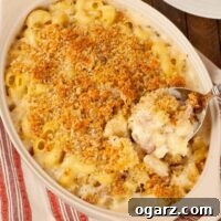 A casserole of French macaroni and cheese topped with toasted breadcrumbs with a spoonful being scooped out for serving.
