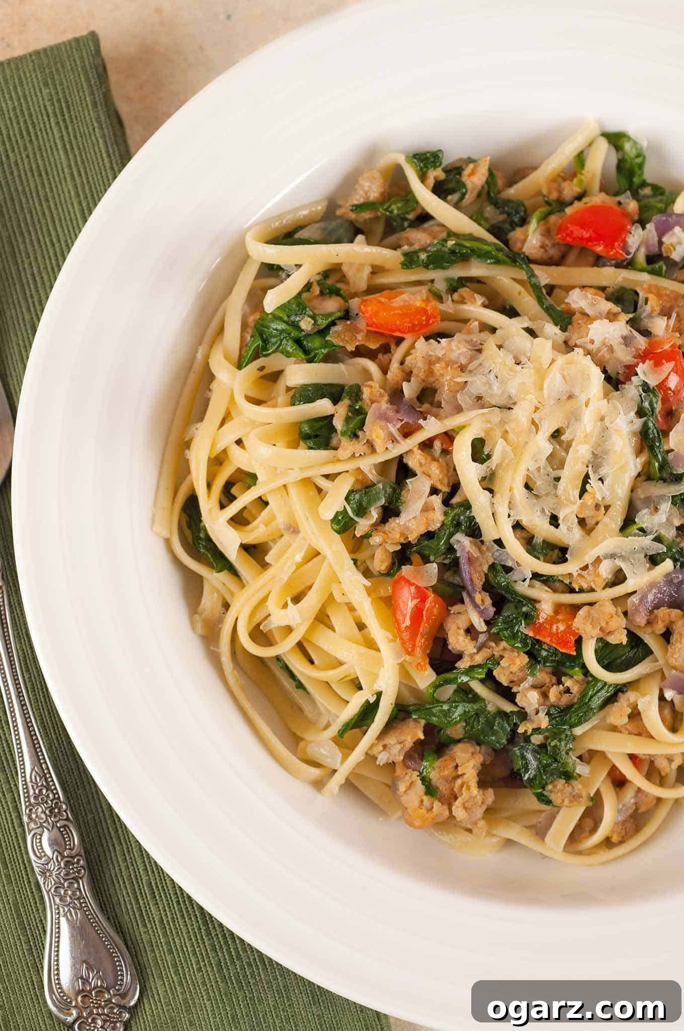 Hearty Sausage and Spinach Pasta 2 A bowl of linguine pasta tossed with crumbled sausage, wilted spinach, red bell peppers, and shredded Parmesan cheese. A perfect quick and easy one-dish dinner.