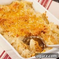 Golden brown roasted cauliflower gratin topped with melted cheddar cheese and crispy breadcrumbs in a white baking dish.