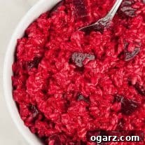 Roasted beet risotto in a white bowl, featuring creamy rice with vibrant red color and chunks of tender beet.