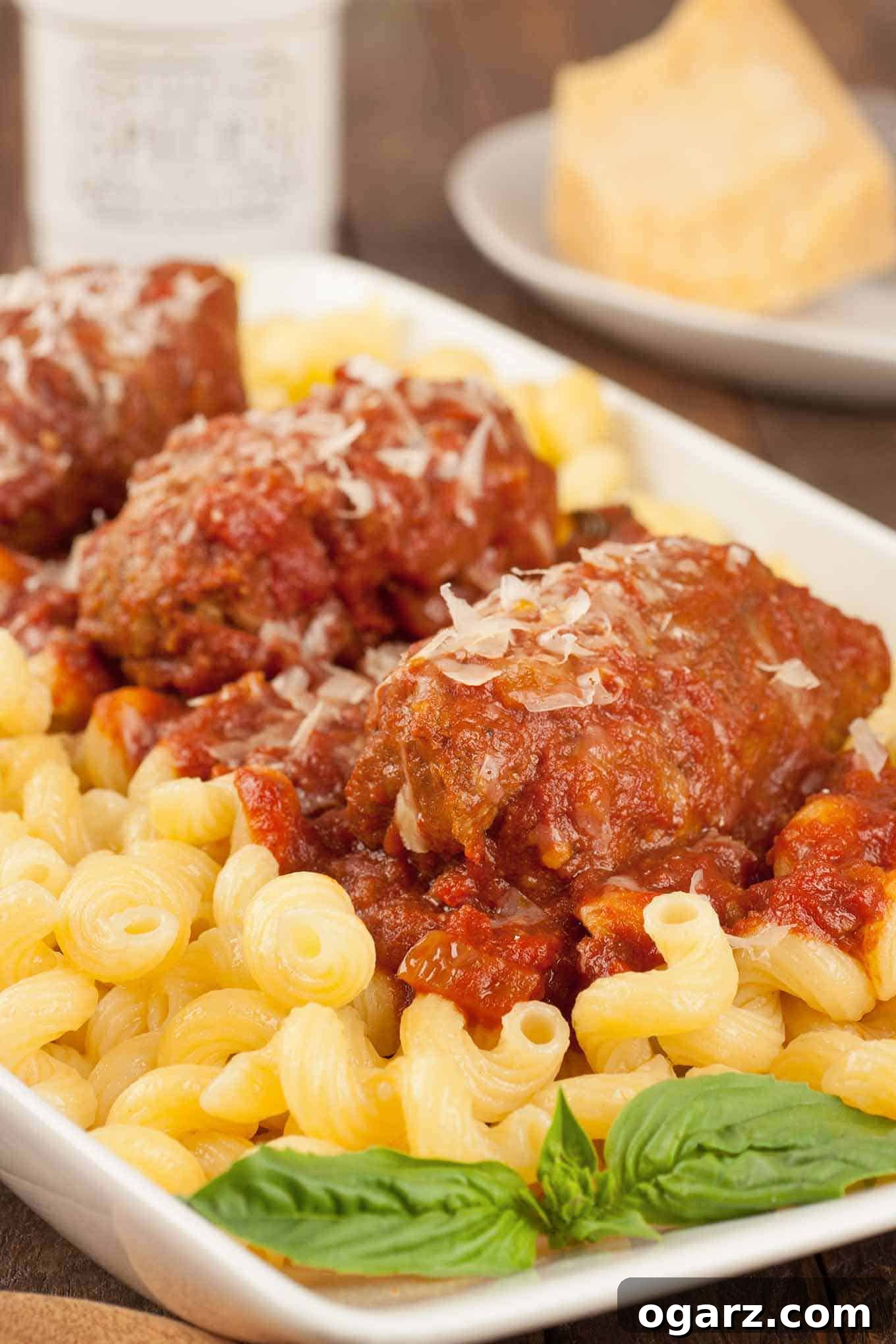 Melt-In-Your-Mouth Slow Cooker Beef Braciole 2 Slow cooker beef braciole topped with tomato sauce and Parmesan, served over cavatappi pasta with fresh basil garnish.